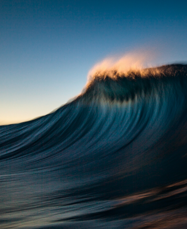 A powerful smooth wave reflecting the sunset.